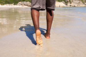View of man walking with bare feet on the beach